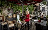 A man in a traditional Bavarian costume sits with a blonde lady in a red dress at the bar in Platzl Karree.