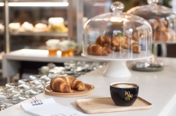 Einige Croissants und ein Cappuccino in einer Tasse der Josefa steht auf einer Theke.