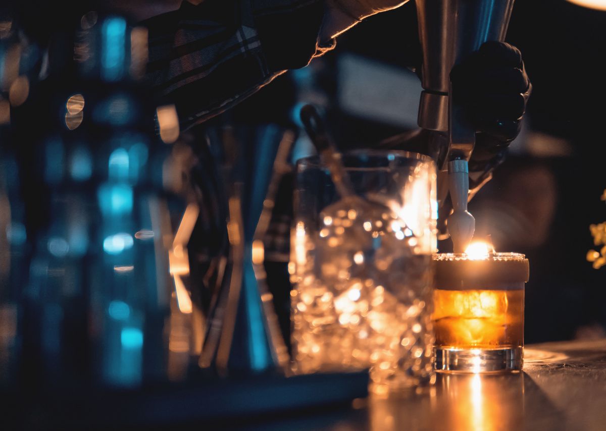 Einem orangen Cocktail wird eine Sahnehaube hinzugefügt